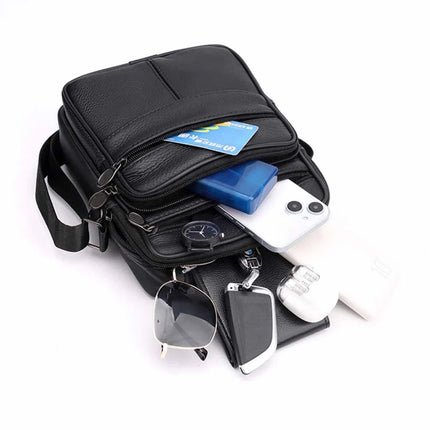 Black leather crossbody bag with phone, wallet, sunglasses, and essentials displayed